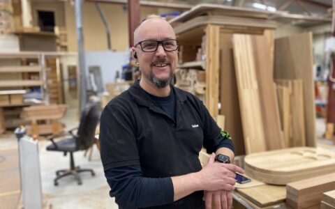 Stefan Axelsson står i maskinparken och ler